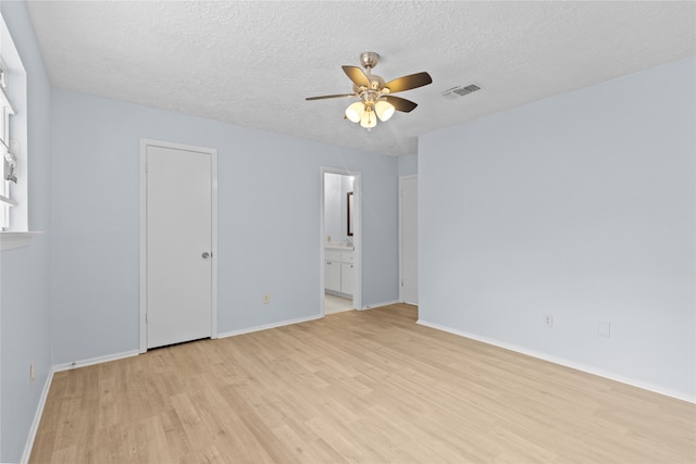 11818 Guadalupe River Dr, Houston, TX 77067 - unfurnished bedroom featuring light wood-style flooring, baseboards, a textured ceiling, ensuite bath, and ceiling fan