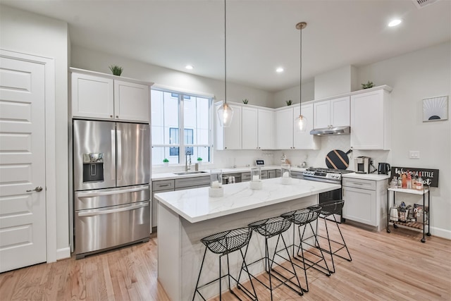 2818 Grand Fountains Dr Unit C, Houston, TX 77054 - kitchen with appliances with stainless steel finishes, under cabinet range hood, a kitchen bar, light wood-style flooring, and recessed lighting