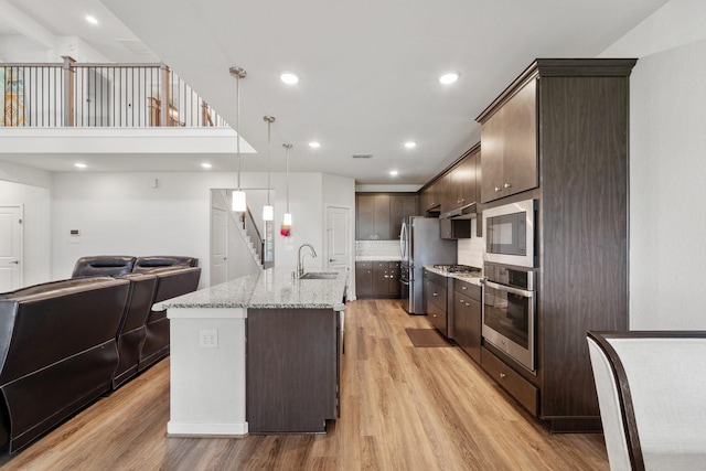 5411 Cavall Rd, Missouri City, TX 77459 - kitchen featuring appliances with stainless steel finishes, dark brown cabinetry, open floor plan, light wood-type flooring, and recessed lighting