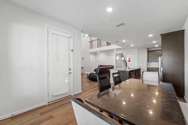 5411 Cavall Rd, Missouri City, TX 77459 - kitchen with light wood-style flooring, freestanding refrigerator, an island with sink, a sink, and dark brown cabinets