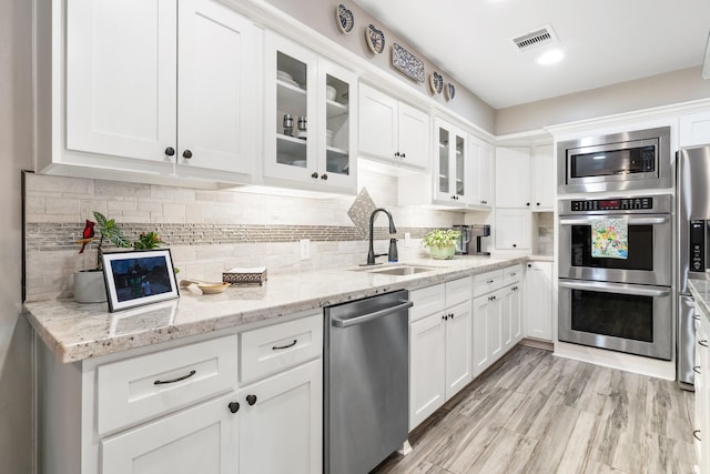 15726 Steamboat Ln, Houston, TX 77079 - kitchen with appliances with stainless steel finishes, a sink, white cabinetry, and glass insert cabinets