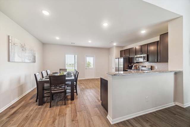1523 Alpine Dr, Rosharon, TX 77583 - kitchen with stainless steel appliances, dark brown cabinets, light wood finished floors, light stone countertops, and recessed lighting