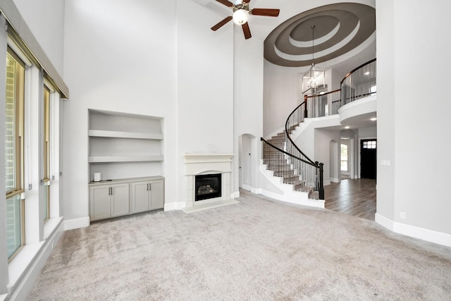 30702 Barred Owl Way, Brookshire, TX 77423 - unfurnished living room with carpet, a towering ceiling, built in features, ceiling fan, and baseboards