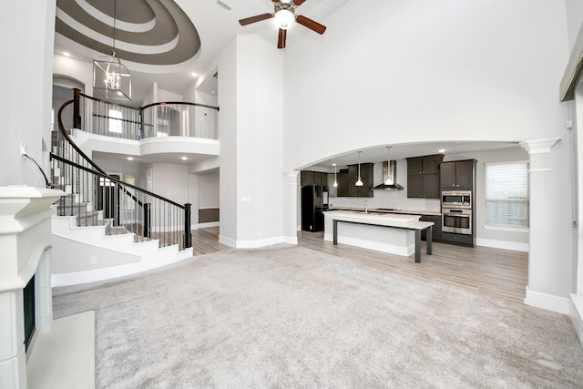 30702 Barred Owl Way, Brookshire, TX 77423 - unfurnished living room with a towering ceiling, baseboards, stairway, a ceiling fan, and a chandelier
