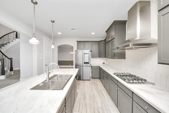 30702 Barred Owl Way, Brookshire, TX 77423 - kitchen featuring wall chimney range hood, appliances with stainless steel finishes, a sink, gray cabinets, and backsplash