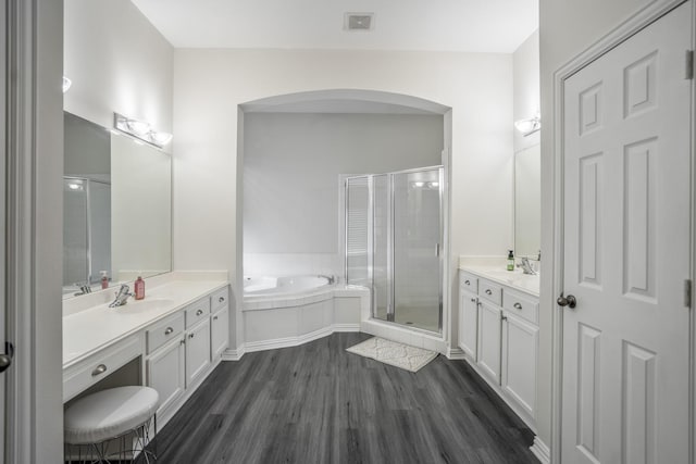 10522 Kirkwell Manor Ct, Spring, TX 77379 - full bathroom featuring two vanities, wood finished floors, a shower stall, a garden tub, and baseboards