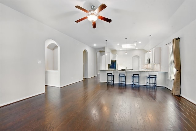22907 Caverly Ln, Tomball, TX 77375 - living room featuring a ceiling fan, dark wood finished floors, arched walkways, recessed lighting, and baseboards
