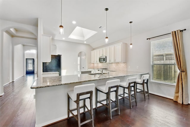 22907 Caverly Ln, Tomball, TX 77375 - kitchen with stainless steel microwave, freestanding refrigerator, arched walkways, a sink, and a peninsula
