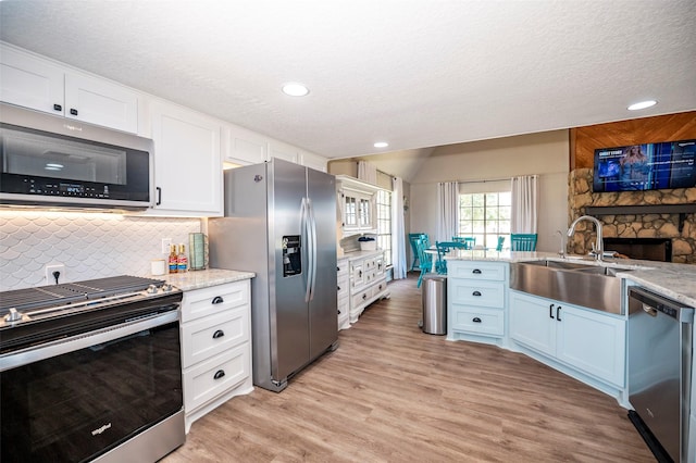 1981 County Road 291, Sargent, TX 77414 - kitchen featuring appliances with stainless steel finishes, a sink, white cabinets, backsplash, and light wood-style floors