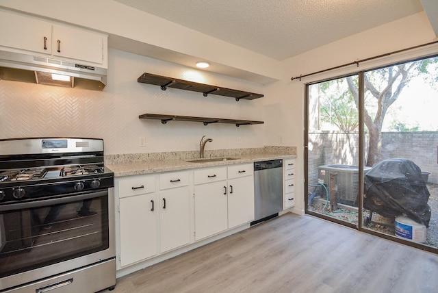 3206 Windchase Blvd Unit 471, Houston, TX 77082 - kitchen featuring appliances with stainless steel finishes, a sink, under cabinet range hood, open shelves, and light wood-style floors