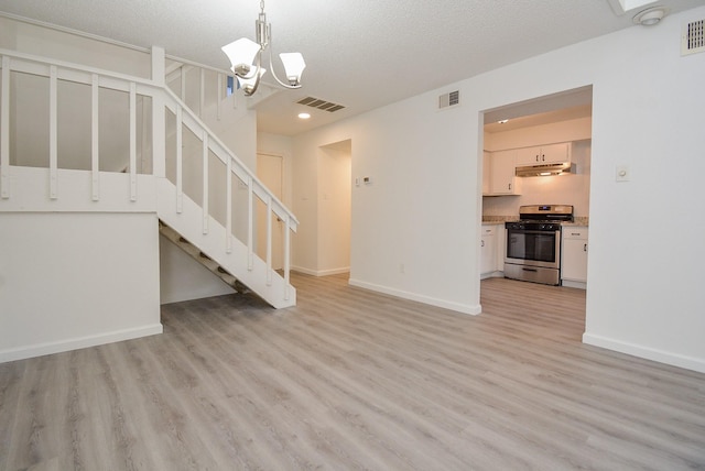3206 Windchase Blvd Unit 471, Houston, TX 77082 - unfurnished living room with stairway, light wood-style flooring, a chandelier, baseboards, and a textured ceiling