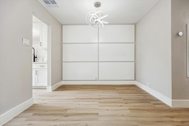 2829 Timmons Ln Unit 174, Houston, TX 77027 - unfurnished dining area with light wood-style flooring, baseboards, and a chandelier