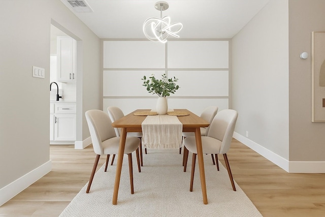 2829 Timmons Ln Unit 174, Houston, TX 77027 - dining room with baseboards, light wood-style flooring, and a chandelier