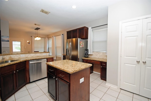 9723 Therrell Dr, Houston, TX 77064 - kitchen featuring appliances with stainless steel finishes, a sink, decorative backsplash, hanging light fixtures, and light tile patterned floors