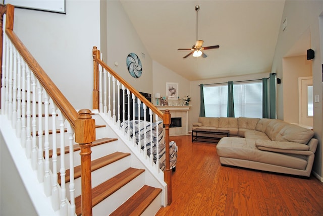 9723 Therrell Dr, Houston, TX 77064 - living room featuring ceiling fan, wood finished floors, a tile fireplace, high vaulted ceiling, and stairs