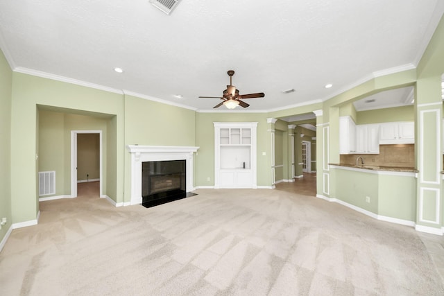 22127 Glen Arden Ln, Katy, TX 77450 - unfurnished living room with ceiling fan, decorative columns, light colored carpet, ornamental molding, and a fireplace with flush hearth