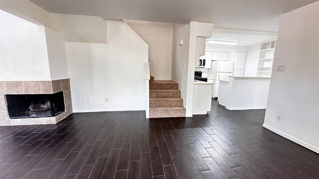 16800 Sugar Pine Dr Unit C21, Houston, TX 77090 - unfurnished living room featuring dark wood-style floors, baseboards, stairs, and a tiled fireplace