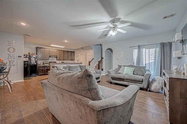 2827 Silver Charm, Houston, TX 77014 - living area with arched walkways, a ceiling fan, stairs, light wood finished floors, and baseboards