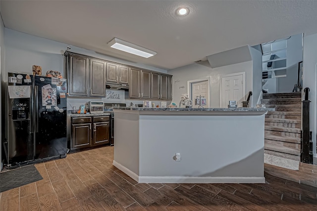 2827 Silver Charm, Houston, TX 77014 - kitchen featuring black fridge, dark wood finished floors, dark brown cabinetry, under cabinet range hood, and electric range