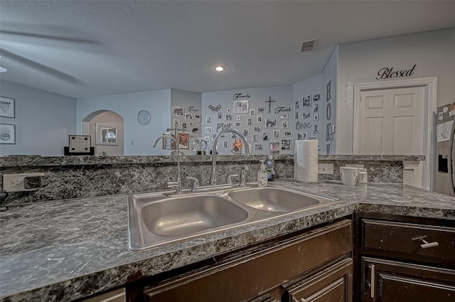 2827 Silver Charm, Houston, TX 77014 - kitchen featuring a sink, dark brown cabinets, arched walkways, and dark countertops