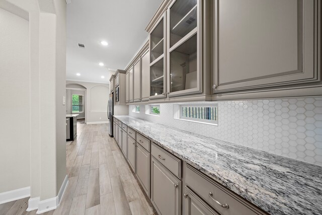 4021 Windsor Chase Dr, Spring, TX 77386 - kitchen featuring arched walkways, gray cabinets, baseboards, backsplash, and crown molding