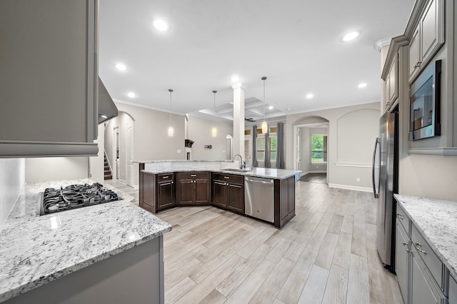 4021 Windsor Chase Dr, Spring, TX 77386 - kitchen with stainless steel appliances, a sink, ornamental molding, arched walkways, and light wood-type flooring