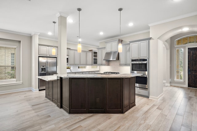4021 Windsor Chase Dr, Spring, TX 77386 - kitchen featuring appliances with stainless steel finishes, under cabinet range hood, baseboards, light wood-style flooring, and a large island