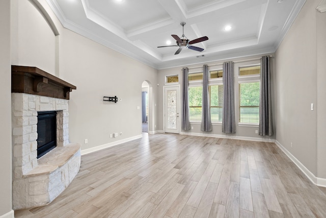 4021 Windsor Chase Dr, Spring, TX 77386 - unfurnished living room featuring a ceiling fan, arched walkways, beam ceiling, a stone fireplace, and light wood-style floors