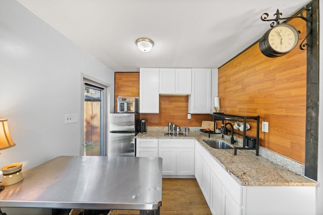 3431 Bristlecone Trl, Spring, TX 77380 - kitchen featuring white cabinets, a sink, wood finished floors, light stone countertops, and wood walls