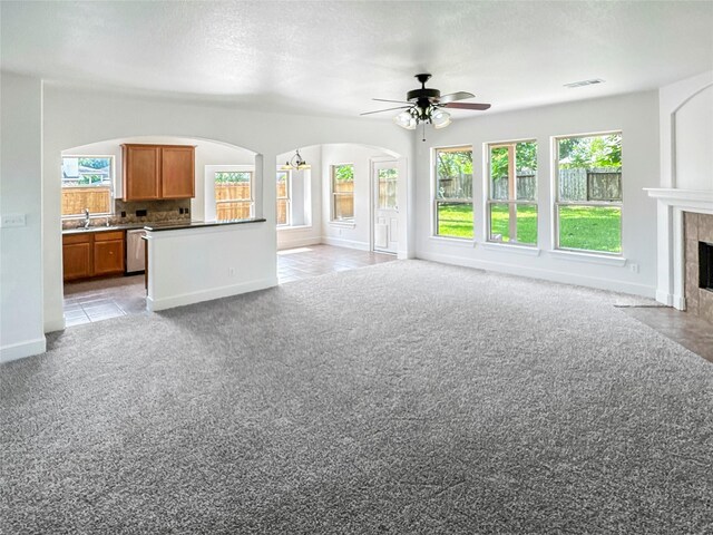 16019 Rustlers Trail Ln, Cypress, TX 77429 - unfurnished living room with arched walkways, ceiling fan, a tile fireplace, light carpet, and baseboards