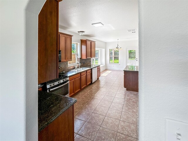 16019 Rustlers Trail Ln, Cypress, TX 77429 - kitchen featuring appliances with stainless steel finishes, decorative backsplash, a sink, brown cabinetry, and light tile patterned floors