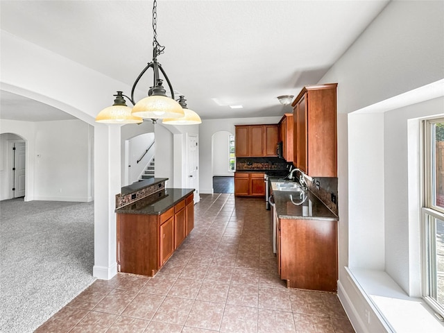 16019 Rustlers Trail Ln, Cypress, TX 77429 - kitchen with arched walkways, brown cabinets, baseboards, and light tile patterned floors