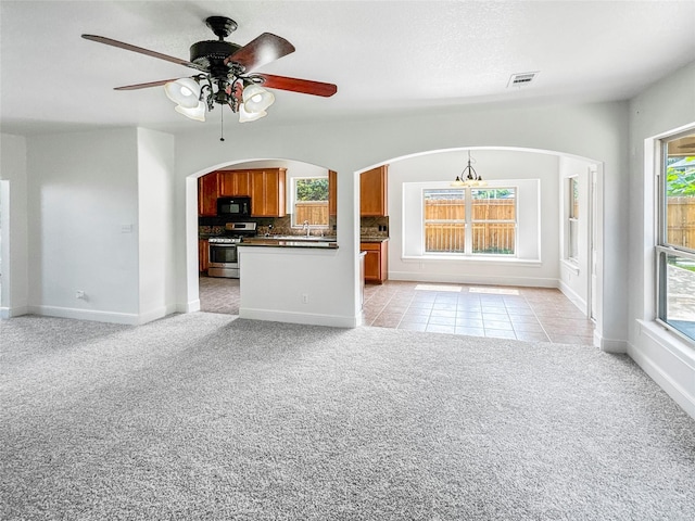 16019 Rustlers Trail Ln, Cypress, TX 77429 - unfurnished living room with light colored carpet, ceiling fan, baseboards, a sink, and arched walkways