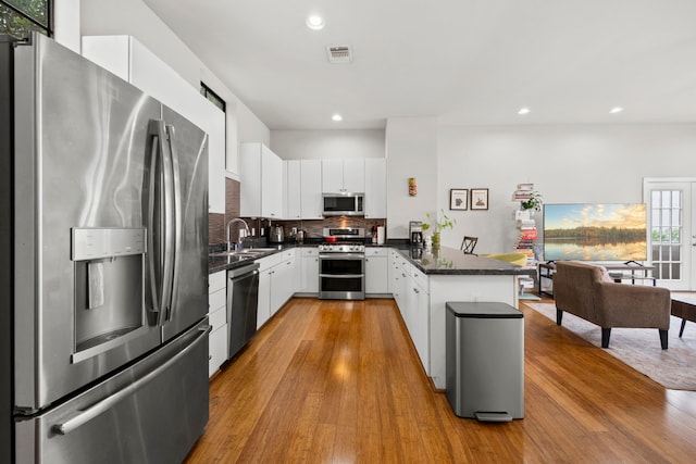 939 Colorado St Unit 22, Houston, TX 77007 - kitchen with appliances with stainless steel finishes, a sink, a peninsula, dark countertops, and wood finished floors