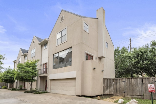 939 Colorado St Unit 22, Houston, TX 77007 - view of front facade with stucco siding, driveway, a garage, and a chimney