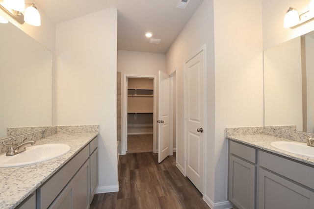 26449 Lakeshore Dr, Hempstead, TX 77445 - bathroom with wood finished floors, two vanities, baseboards, a walk in closet, and recessed lighting