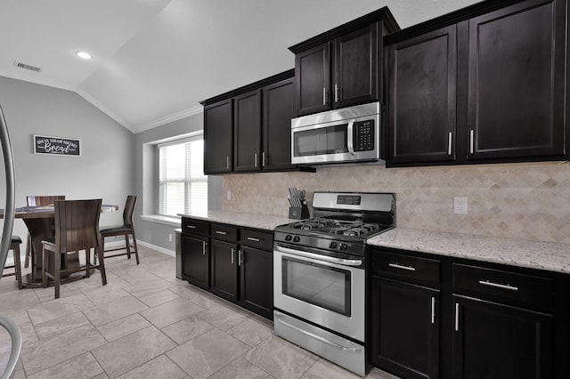 3921 Enchanted Timbers Ln, Spring, TX 77386 - kitchen with stainless steel appliances, vaulted ceiling, dark cabinetry, ornamental molding, and backsplash
