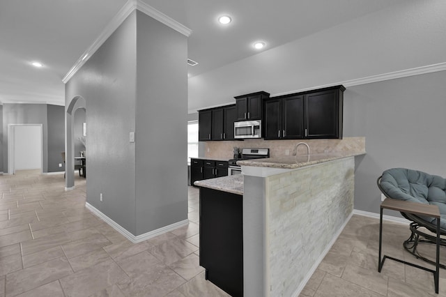 3921 Enchanted Timbers Ln, Spring, TX 77386 - kitchen with appliances with stainless steel finishes, dark cabinetry, arched walkways, crown molding, and tasteful backsplash