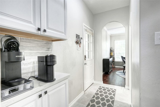 8507 Marchelle Ln, Spring, TX 77379 - kitchen with arched walkways, white cabinets, baseboards, crown molding, and light stone counters