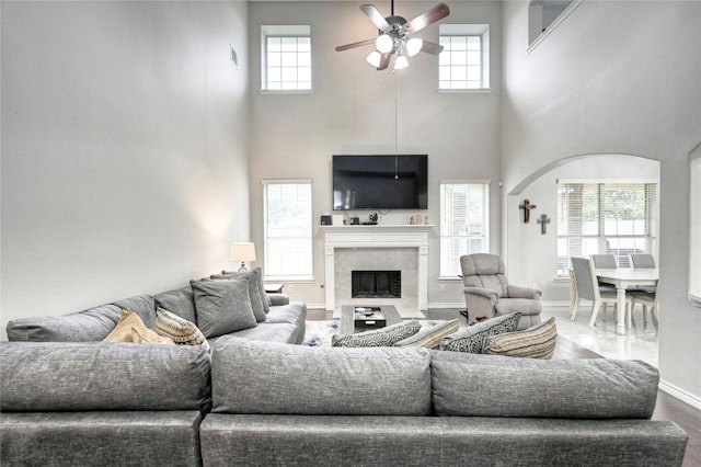 8507 Marchelle Ln, Spring, TX 77379 - living area with a ceiling fan, a high ceiling, a tiled fireplace, baseboards, and arched walkways