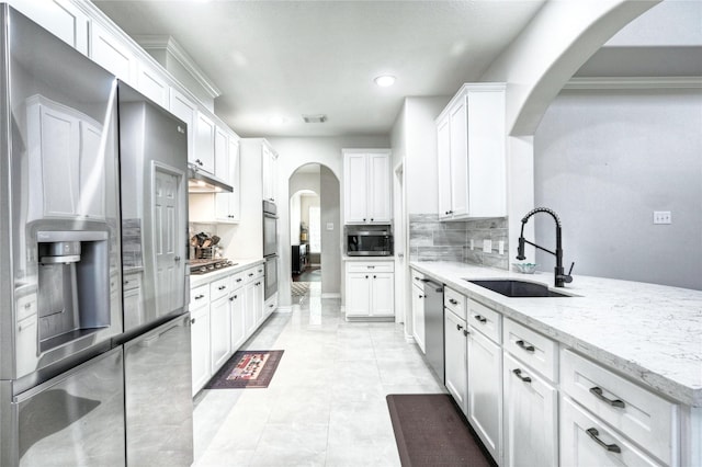 8507 Marchelle Ln, Spring, TX 77379 - kitchen featuring a sink, appliances with stainless steel finishes, under cabinet range hood, arched walkways, and decorative backsplash
