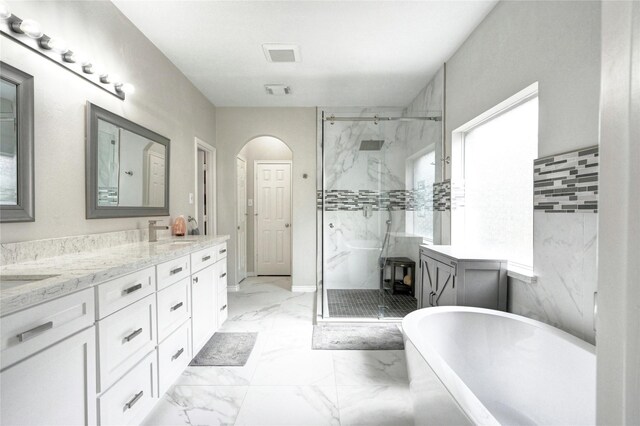 8507 Marchelle Ln, Spring, TX 77379 - bathroom featuring marble finish floors, a marble finish shower, a freestanding tub, double vanity, and healthy amount of natural light