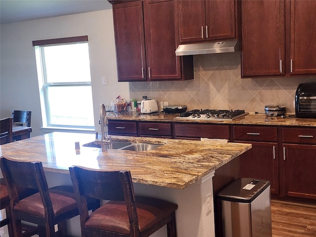 6006 Thief River Falls Dr, Katy, TX 77493 - kitchen with a sink, under cabinet range hood, light stone counters, and a kitchen bar