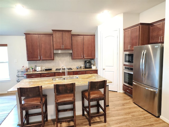 6006 Thief River Falls Dr, Katy, TX 77493 - kitchen with appliances with stainless steel finishes, a sink, under cabinet range hood, backsplash, and a kitchen breakfast bar