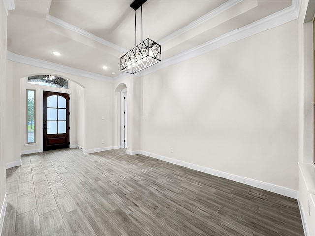 258 Monterrey Rd, Montgomery, TX 77356 - unfurnished dining area with arched walkways, a raised ceiling, baseboards, wood finished floors, and crown molding