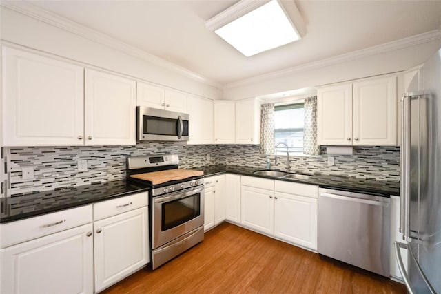 10907 Overlea Dr, Houston, TX 77089 - kitchen featuring appliances with stainless steel finishes, a sink, dark countertops, crown molding, and light wood-style floors