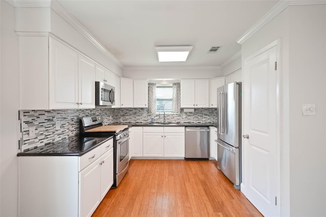 10907 Overlea Dr, Houston, TX 77089 - kitchen with stainless steel appliances, a sink, dark countertops, light wood-type flooring, and white cabinetry