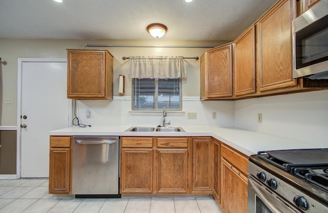 10829 E Linwood Dr, La Porte, TX 77571 - kitchen featuring appliances with stainless steel finishes, a sink, brown cabinetry, light countertops, and a textured ceiling