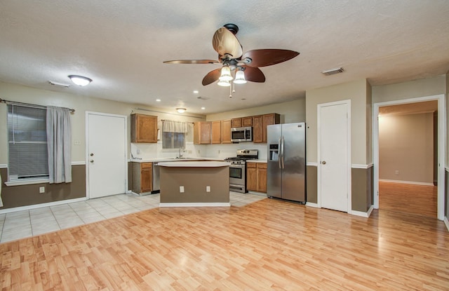 10829 E Linwood Dr, La Porte, TX 77571 - kitchen with appliances with stainless steel finishes, light wood finished floors, a ceiling fan, light countertops, and a center island