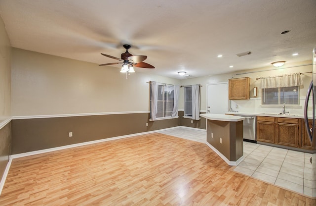 10829 E Linwood Dr, La Porte, TX 77571 - kitchen featuring stainless steel dishwasher, a sink, light wood-style flooring, ceiling fan, and a center island